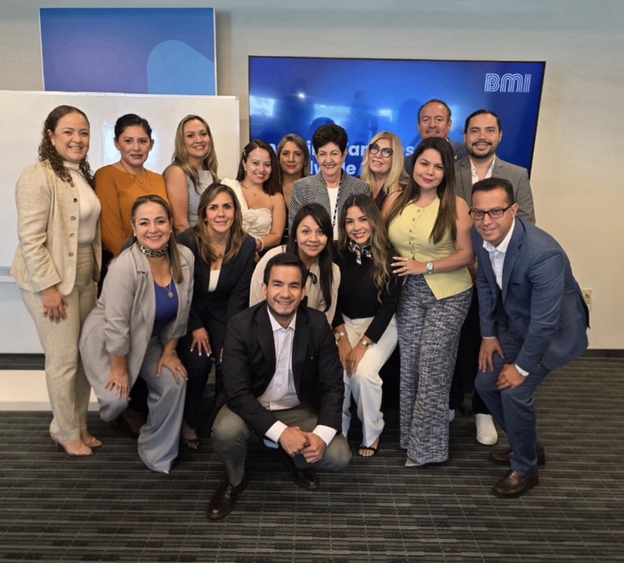 Asesores de Legacy posando frente a la pantalla de BMI en un evento corporativo