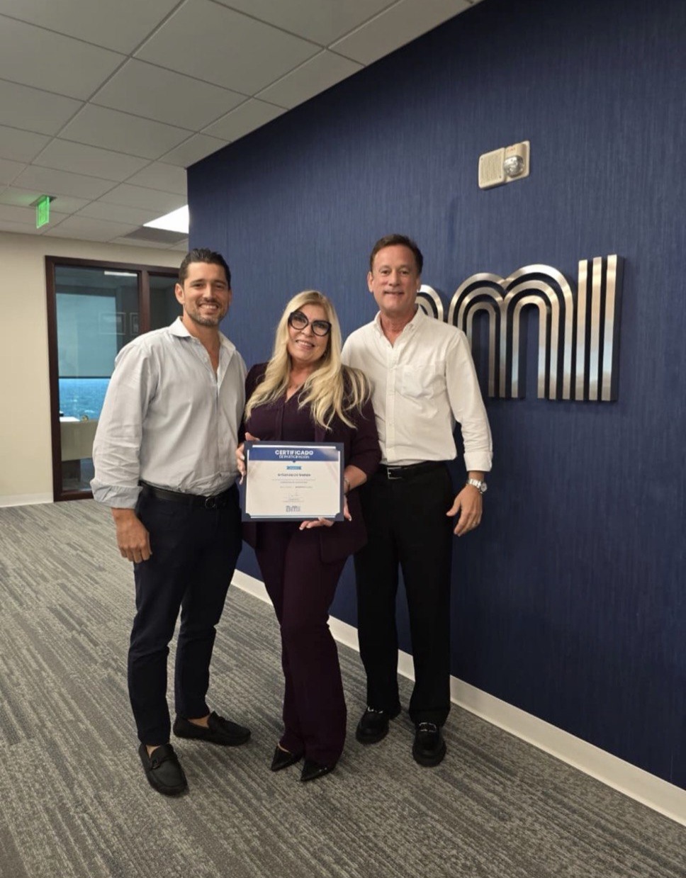 Griselda recibiendo un certificado de participación de BMI junto a dos ejecutivos