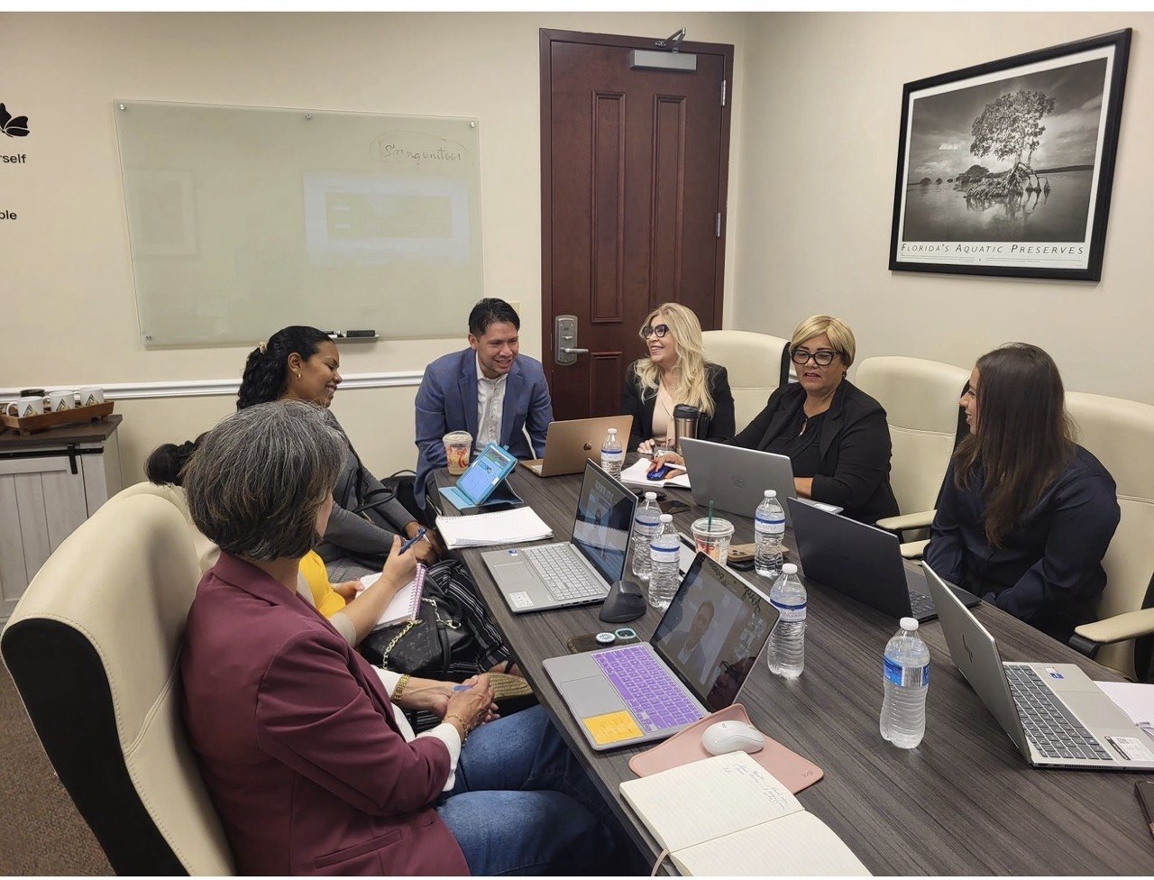 Asesores de Legacy colaborando con sus laptops alrededor de la mesa de juntas
