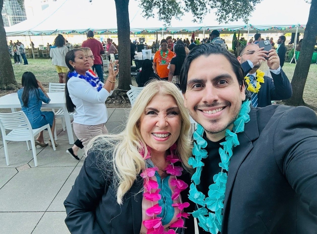 Griselda y colega en evento al aire libre con collares tropicales