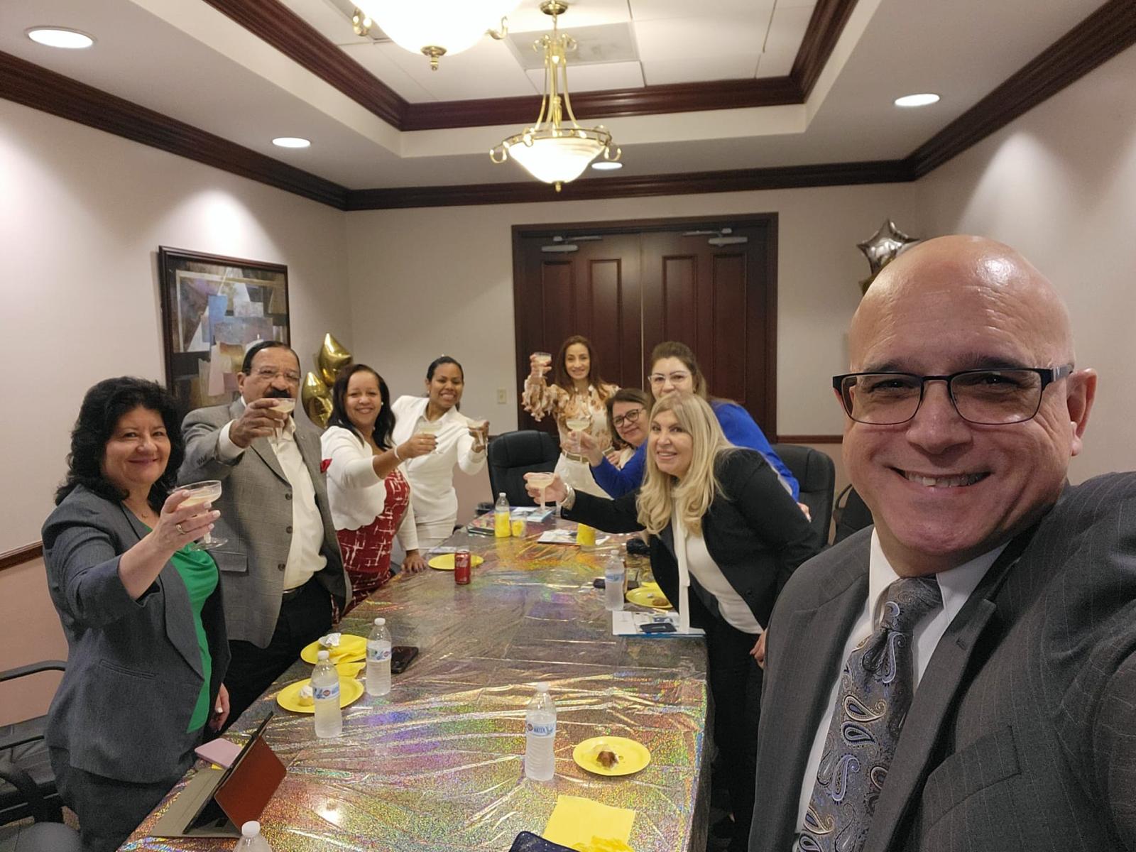 Equipo de Legacy brindando alrededor de la mesa de reuniones en una celebración de oficina